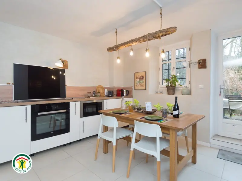 Le séjour-cuisine du gîte, table dressée et porte-fenêtre ouvrant sur le jardin