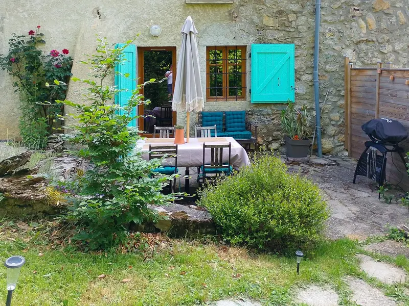 Le coin repas extérieur et le barbecue, vus depuis le jardin